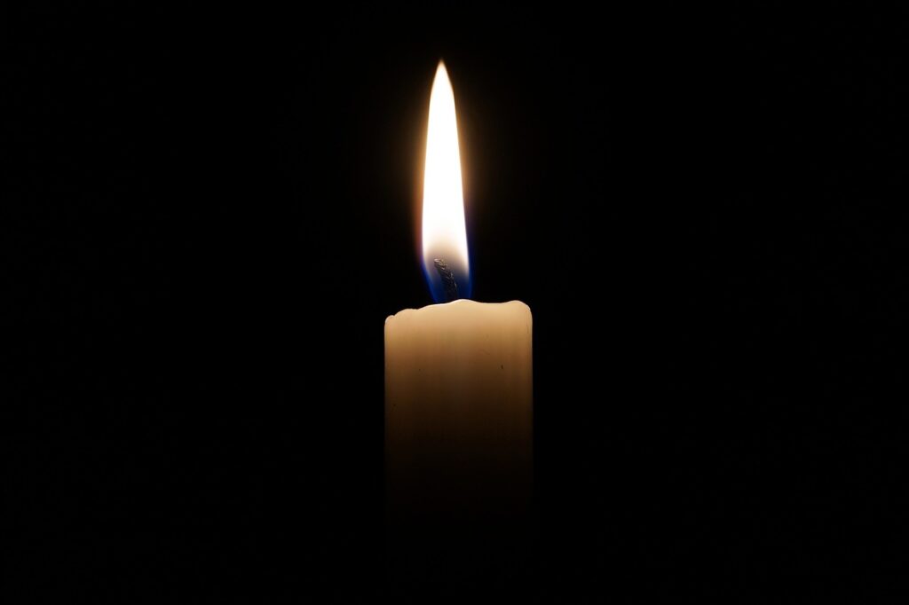 a single candle burns in the dark